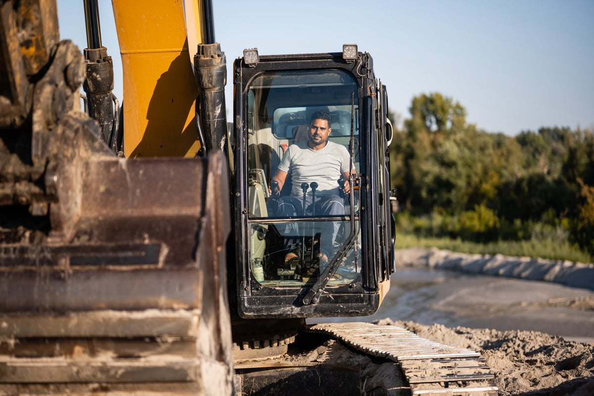 Bauarbeiter bedient Baumaschine auf Baustelle