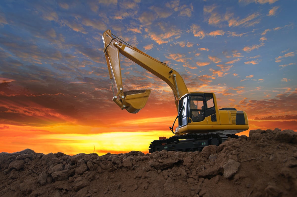 Bagger bei Erdarbeiten auf Baustelle bei Sonnenuntergang
