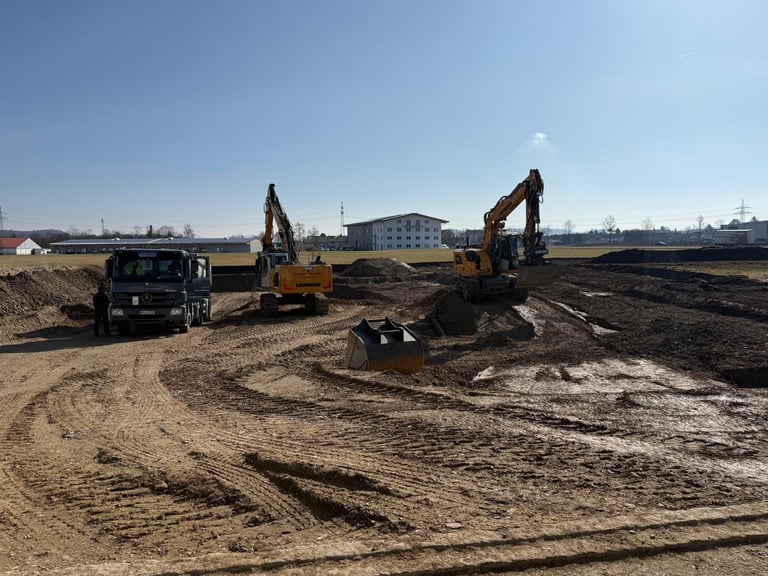 Baustelle mit Baggern und schweren Maschinen im Einsatz auf Erdreich unter klarem blauem Himmel